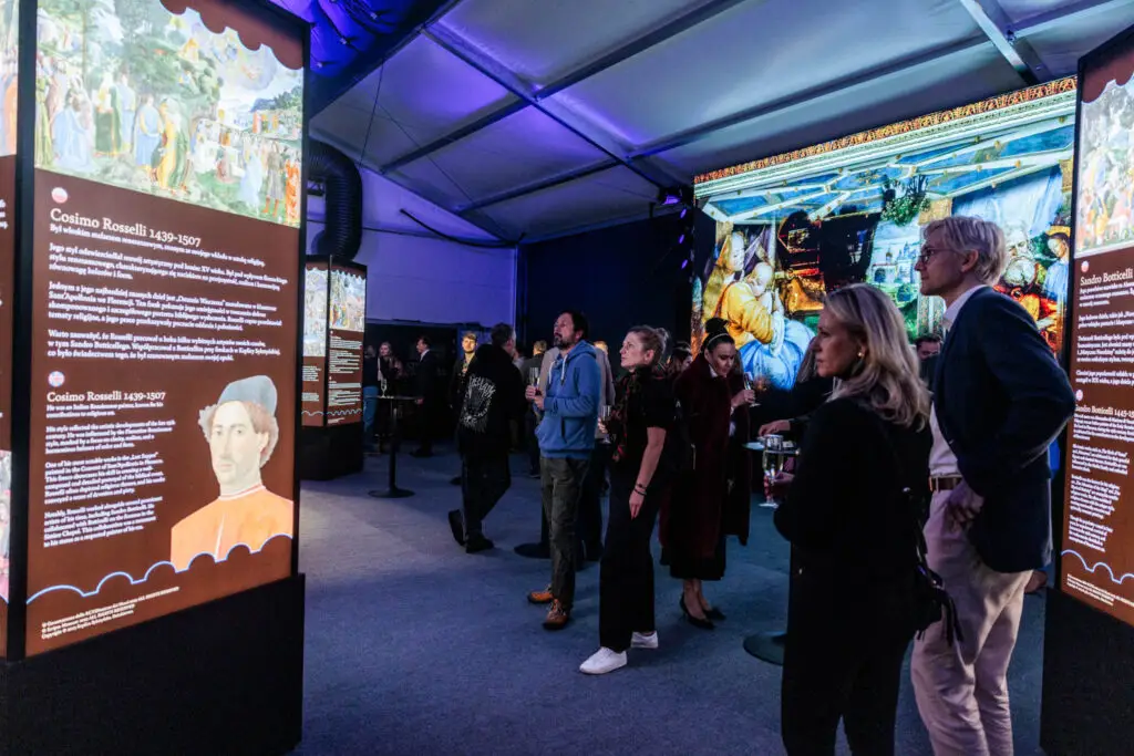 A group of people standing around in front of a screen.